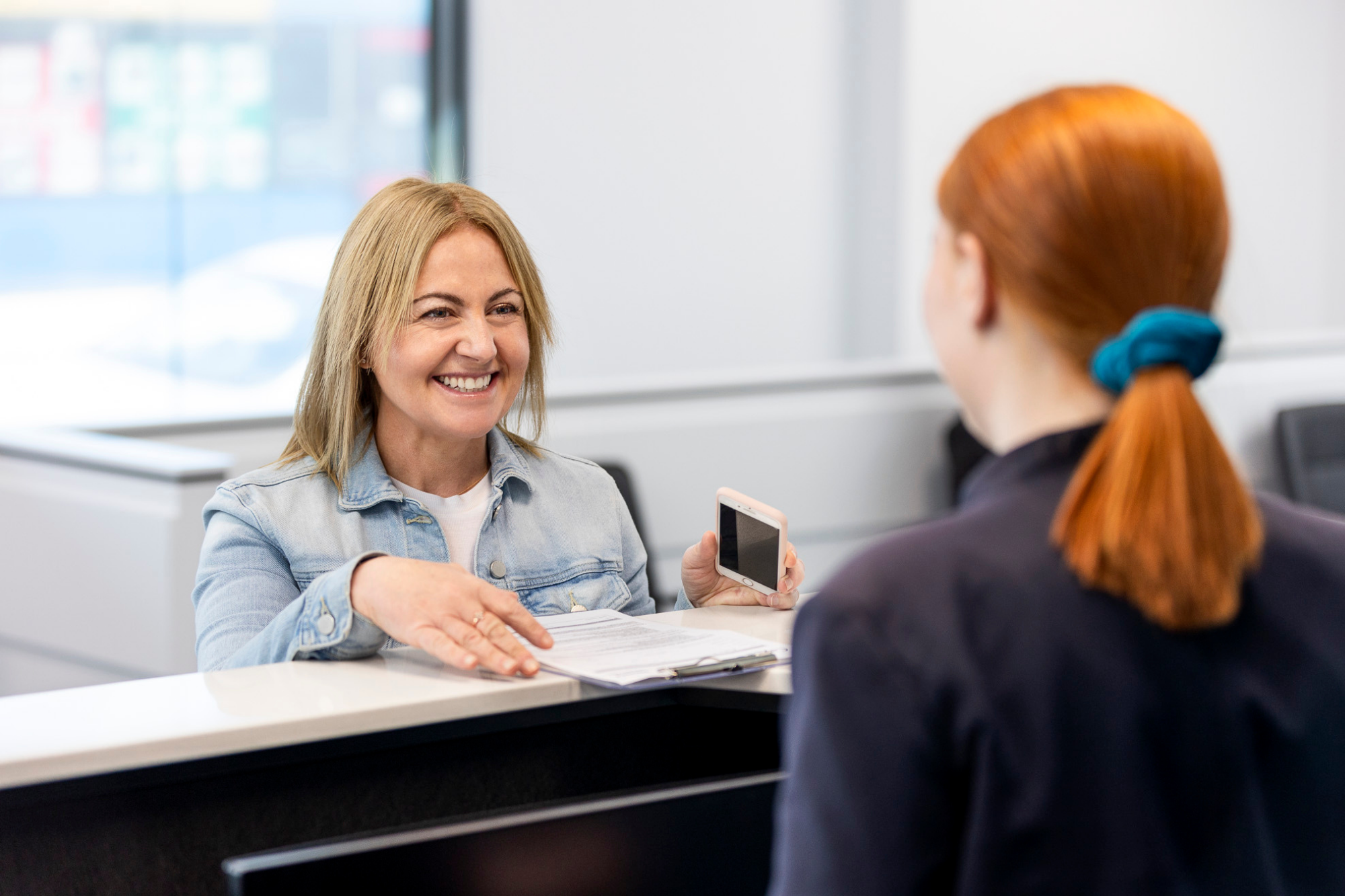 Smiling Woman Holding Documents for Fees and Billing | Medical Imaging Services | FMIG